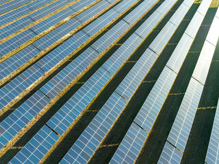 Aerial view of a solar farm. Rows of solar panels are arranged in a neat, grid-like pattern,...