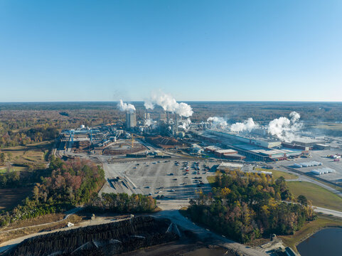Aerial view of a large industrial complex, which is a paper mill. Smoke coming from the mill causing air pollution.