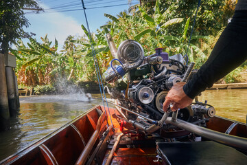 Powerful engine of traditional long tail boat in Thailand. Hand of drive control boat in narrow...