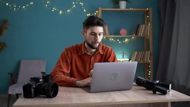Male photographer transfer picture in memory card put laptop, Handsome man working on laptop with camera at home office