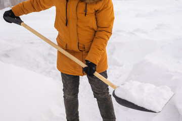 Close-up man cleans and clears the snow in front of the house on frosty day. Cleaning the street...