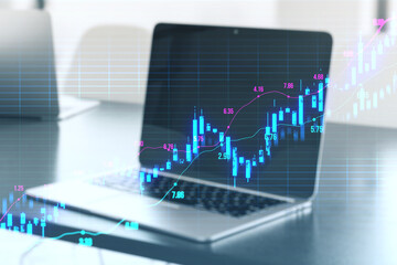 Close up of laptop on office desk with glowing upward candlestick forex chart on blurry grid background. Trade, finance and money concept. 3D Rendering.