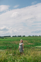 Fototapeta na wymiar A beautiful girl walks in a field in the summer, general plan