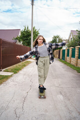 Beautiful teen girl in a plaid shirt riding a skateboard