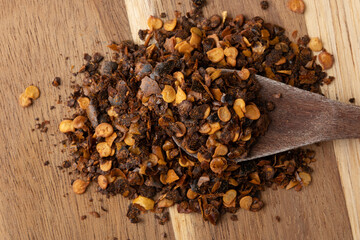 Red pepper flakes on spoon, top view. Selective focus.