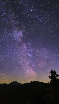 Milky way universe, star trails in dark evening clouds. Perseid Meteor Shower, Timelapse, vertical