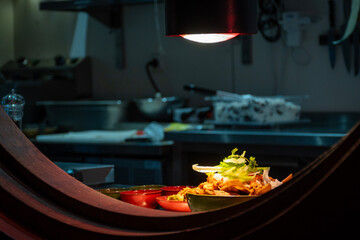 A gourmet fancy version of homemade street food nachos and, cheese and cilantro garnish. Snack food Mexican meal served in brown dish bowl placed in window by chef in kitchen hole ready to be served