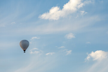 Hot air balloon silhouette in blue sky with white clouds. Photo from below