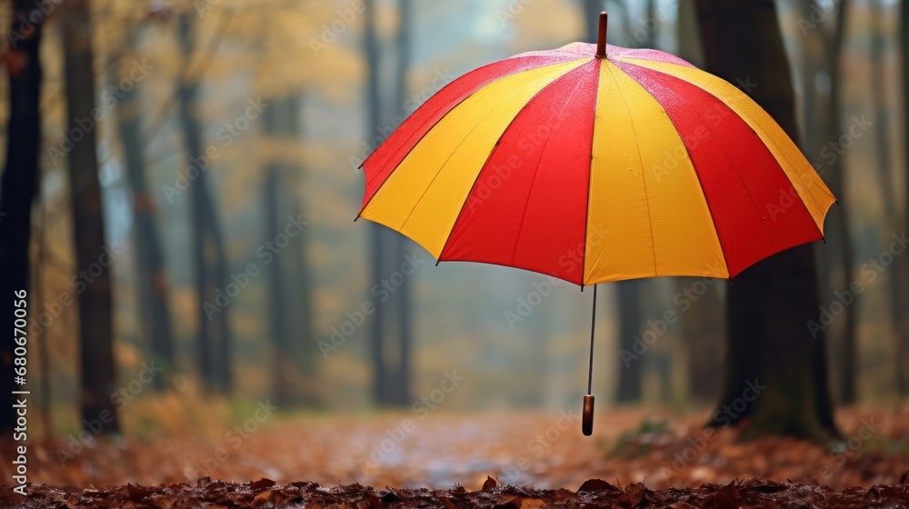 Poster a red and yellow umbrella is in the middle of a leaf covered path in a wooded area with trees in the