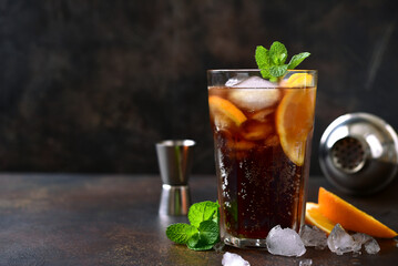 Cold summer soda cocktail with cola, dark rum and orange in a tall glass.
