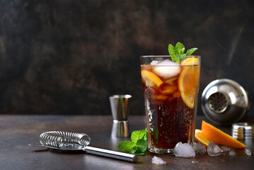 Cold summer soda cocktail with cola, dark rum and orange in a tall glass.