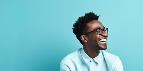 portrait of a smiling young black man wearing glasses with blue shirt and blue background copy space
