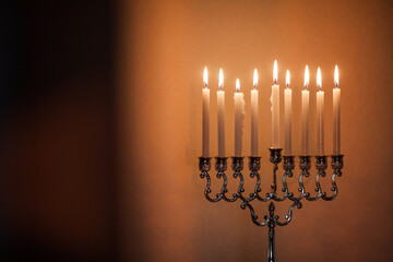 Closeup of Hanukkah menorah, or hanukkiah in the light of the sun at sunset for Jewish holiday Hanukkah. Hanukkah lamp, nine-branched candelabrum with burning candles.