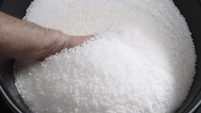 A factory worker checks plastic pellets before they are put into production. White compound in a man's hand. Production