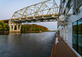 Mississippi river cruise boat sails towards Mark Twain Memorial road bridge near Hannibal, Missouri at sunrise