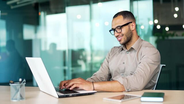 happy handsome business man working laptop computer at workplace in office desk. Male typing, browsing, chatting on PC uses Internet, generates job tasks using AI artificial intelligence satisfied