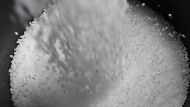 Filling the tank with plastic granules. The process of producing parts from polyethylene compound. White granules are poured into a container.
