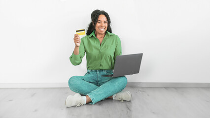 Black woman using laptop and credit card for transaction indoor