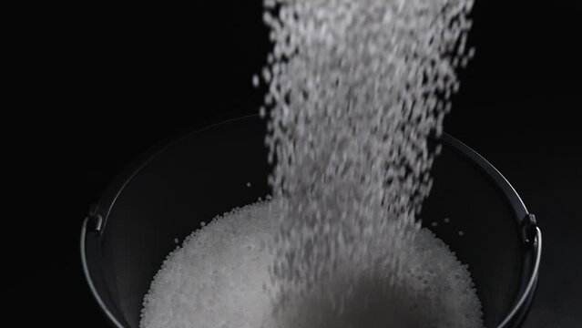 Filling the tank with plastic granules. The process of producing parts from polyethylene compound. White granules are poured into a container.
