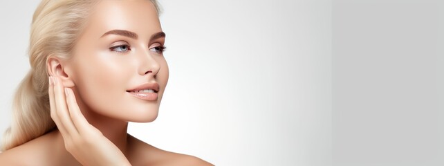 Photograph of a female model with clean and healthy skin touching her face, taken on a studio background.