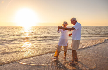 Happy Senior Old Retired Couple Walking Dancing Holding Hands on Beach at Sunset - 680690065