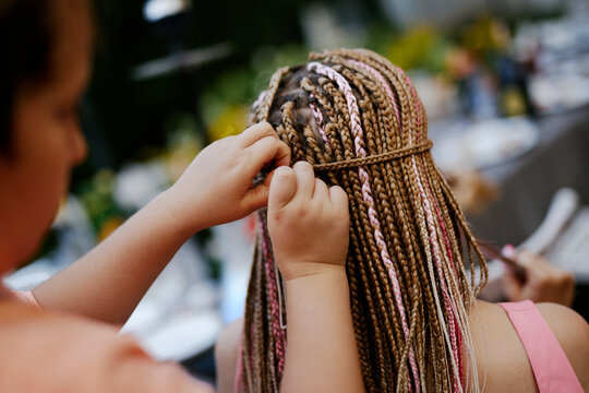 Braiding African pigtails with colored ribbons