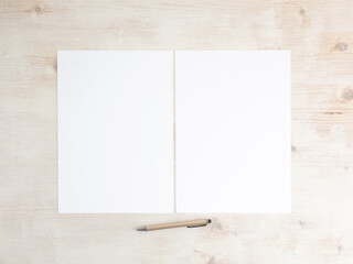 Papers A4 two empty on wooden table with pen. Office stationery mockup flat lay.