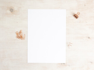 Paper A4 empty on wooden table with paperclips and pins. Office stationery mockup flat lay.