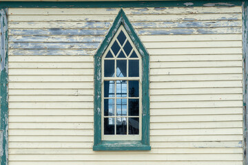 The exterior wall of a religious building with pale yellow colored narrow horizontal clapboard...