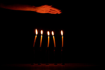 A woman s hand next to shell casings in which candles are burning in the dark, pain and loss of...