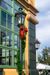 A tall festive black street lamp with a vibrant red bow in front of a vintage-style shot. The front...