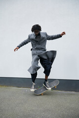 Stylish black man with locs doing skateboard tricks on sidewalk © Ejatu Shaw