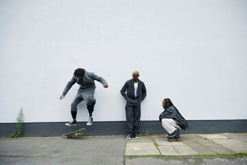 Group of three black and fashionable friends hanging out together outdoors with their skateboards and rollerskates © Ejatu Shaw
