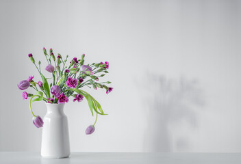 spring purple flowers on white shelf on background wall