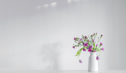 spring purple flowers on white shelf on background wall