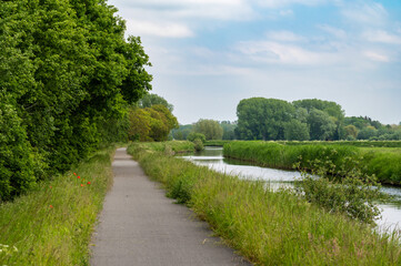 Fototapeta na wymiar Biking path alongside the banks of the canal of Stekene, Flemish Region, Belgium