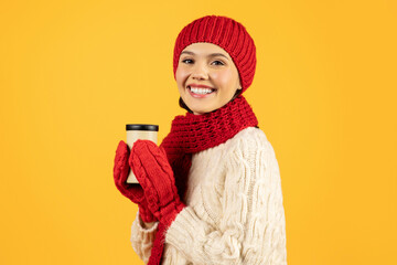 Happy lady holds cup of hot coffee on yellow background - obrazy, fototapety, plakaty