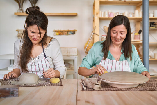 Two women with apron making pottery crafts in a workshop. Hobby and craft concept.