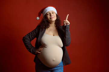 Authentic pregnant woman in third trimester of her happy carefree pregnancy, smiles and points...
