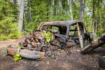 Fototapeta na wymiar Old abandoned car wreck hidden in a forest, famous dark tourism destination in Sweden