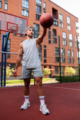 A man is holding a ball on an outdoor basketball court