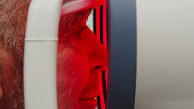 Close-up, vision test. An elderly man checks his vision through a biometer in a modern clinic with new medical technologies.
