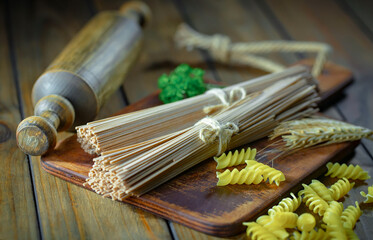 Raw pasta, spaghetti in a plate with seasonings and vegetables. Raw, ready-to-cook dish.