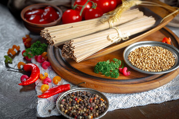 Raw pasta, spaghetti in a plate with seasonings and vegetables. Raw, ready-to-cook dish.
