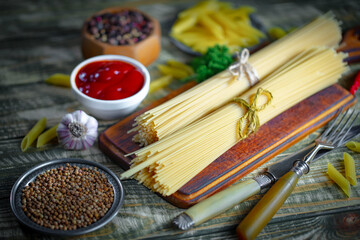 Raw pasta, spaghetti in a plate with seasonings and vegetables. Raw, ready-to-cook dish.