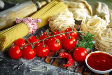 Raw pasta in composition with kitchen accessories in the kitchen on the table.