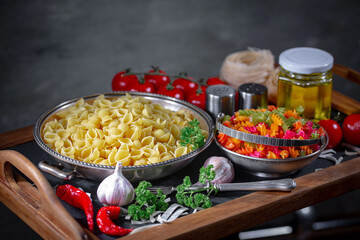 Raw pasta in composition with vegetables in the kitchen.