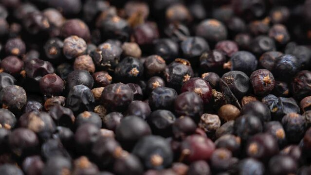 A pile of dried juniper berries close up. Natural seasoning. Rotation. Macro shot