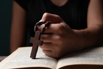 woman with holy bible and cross on black background
