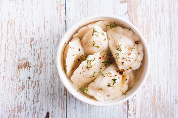 Close up of traditional dumplings soup with herbs and spices in a bowl on the table top view